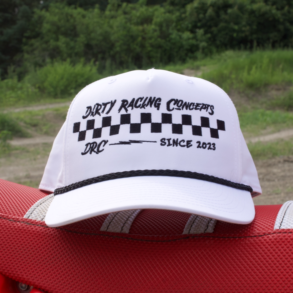 White cap with black text and checkered pattern on a red car seat outdoors.