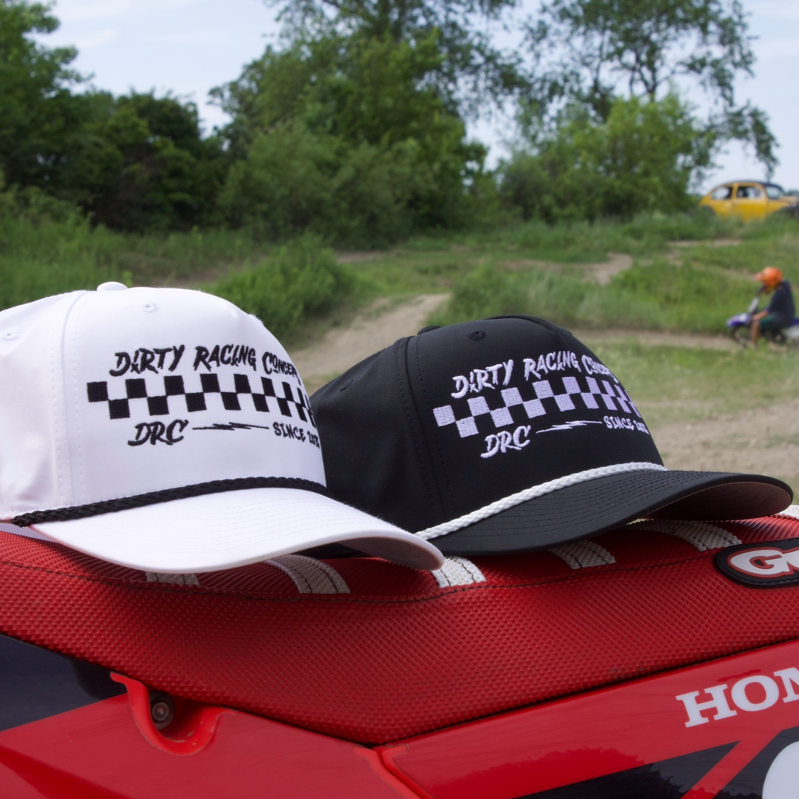 Two hats on a red Honda motorcycle with a natural background